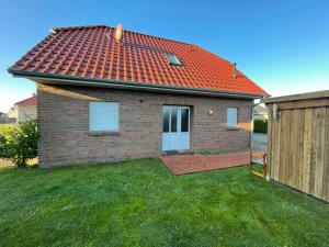 a small brick house with a red roof at Wangernest in Wangerland