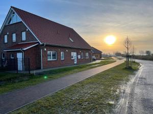 a house on the side of a road with the sunset at Wangeroase in Wangerland