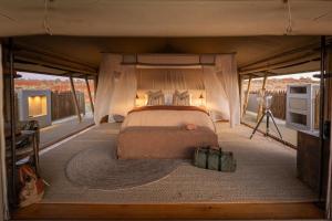 a bed in a tent with a camera at Wolwedans Dune Camp in NamibRand