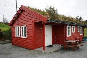 a red building with a grass roof and a bench at Haraldshaugen Camping in Haugesund