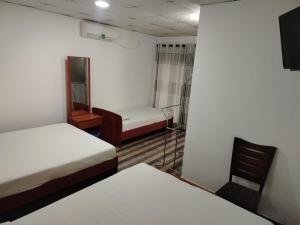 a room with two beds and a chair and a tv at Sathkara Guest House in Anuradhapura