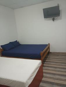 a bedroom with two beds and a tv on the wall at Sathkara Guest House in Anuradhapura +3 photos