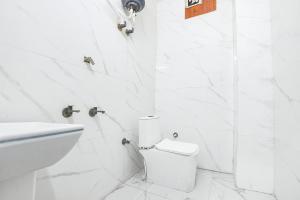 a white bathroom with a toilet and a sink at FabHotel Mohini Palace in Vrindāvan