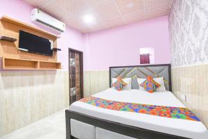 a bedroom with a bed and a flat screen tv at FabHotel Mohini Palace in Vrindāvan