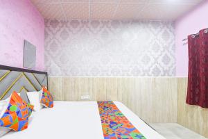 a bedroom with a bed and a pink wall at FabHotel Mohini Palace in Vrindāvan +14 photos