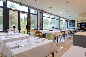 a restaurant with white tables and chairs and windows at AN Hotel Milano San Donato in San Donato Milanese