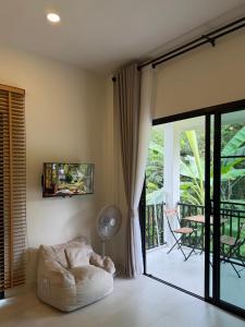 a living room with a couch and a sliding glass door at Moon & Banana in Ko Phangan