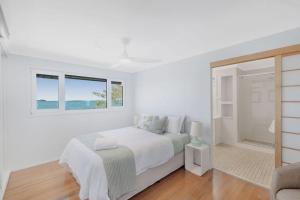 a white bedroom with a bed and a window at Silver Waters | Private Cove | Ocean Views in Zilzie