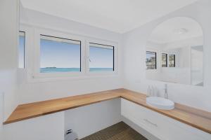 a white bathroom with a sink and windows at Silver Waters | Private Cove | Ocean Views in Zilzie +43 photos