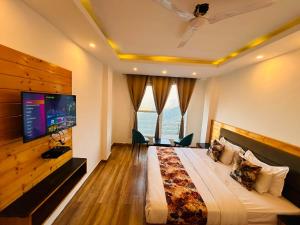 a bedroom with a large bed with a flat screen tv at The Pine Woods - A Four Star Luxury Resort In Mussoorie Near JW Marriott in Mussoorie