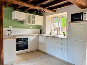 a kitchen with white cabinets and white appliances at Maison de vacances proche de Pontmain in Saint-Mars-sur-la-Futaie +6 photos
