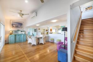 a living room with a staircase and a table and chairs at Silver Waters | Private Cove | Ocean Views in Zilzie