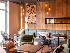 a restaurant with tables and chairs and a couch at Mercure Han-sur-Lesse in Han-sur-Lesse