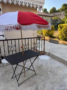 a table with a red umbrella on a patio at Le CRAMPOT in Lectoure +1 photo