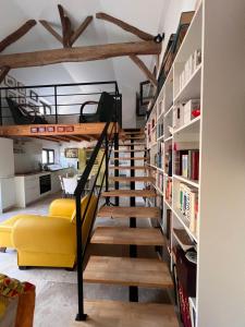 a staircase leading up to a loft with a yellow couch at Le CRAMPOT in Lectoure