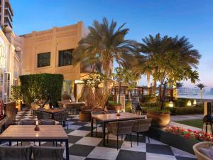 a patio with tables and chairs and palm trees at Fairmont The Palm in Dubai