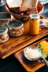 a wooden tray with jars of food and bread at Olive Grove Guesthouse in Windhoek