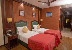 a hotel room with two beds with red sheets at Hotel Atithi in Guwahati