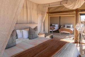 a bedroom with a bed and a room with a fan at Wolwedans Desert lodge in NamibRand