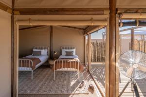 a bedroom with two beds and a fan on a balcony at Wolwedans Desert lodge in NamibRand