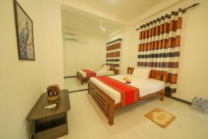 a bedroom with two beds and a table and a television at Ocean villa in Hiriketiya