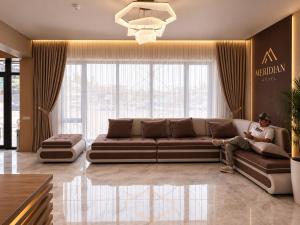 a man sitting on a couch in a living room at Meridian Hotel in Georgīevka