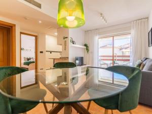 a glass table with green chairs in a living room at Renteando Albir Apartments in Albir