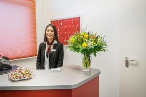 a woman sitting at a counter with a vase of flowers at Signature Hotel Astoria in Hamburg