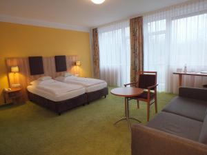 ミュンヘンにあるホテル シュタット パーシングのベッド、テーブル、ソファが備わるホテルルームです。