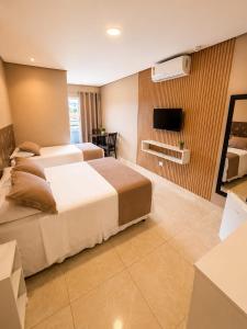 a hotel room with two beds and a flat screen tv at Don Marcos Hotel com Pizzaria in Guarujá