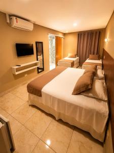 a hotel room with two beds and a flat screen tv at Don Marcos Hotel com Pizzaria in Guarujá +33 photos