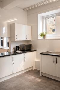 a kitchen with white cabinets and a black counter top at Snowdon Apartments in Stirling