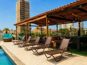 a group of chairs and a pool table on a patio at Don Marcos Hotel com Pizzaria in Guarujá
