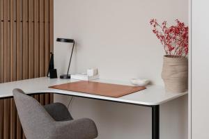 a desk with a chair and a vase of flowers at Unique Tower Business View Apartment in Warsaw