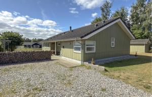 a green house with a stone wall in a yard at Nice Home In Grenaa With Sauna in Grenå