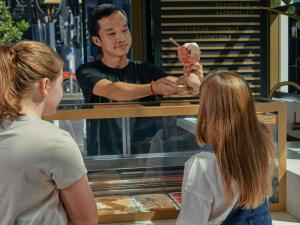 two people standing around a counter with a man selling food at Movenpick Hotel Melbourne On Spencer in Melbourne