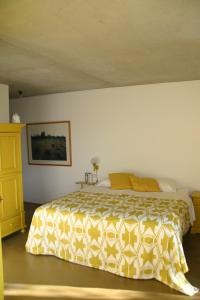 1 dormitorio con 1 cama con colcha amarilla y blanca en De Kemp B&B & Studio's en Vortum-Mullem