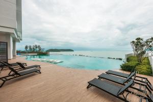 a swimming pool with chairs and a view of the ocean at Assana Cenang Beachview oakville by sync in Pantai Cenang