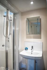 a bathroom with a sink and a shower with a mirror at Arlana Guest House in Cleethorpes