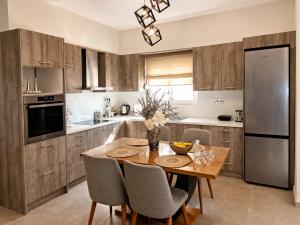 a kitchen with a wooden table with chairs and a refrigerator at Clio's house in Áyioi Dhéka