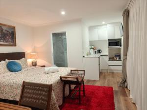a bedroom with a bed and a table and a kitchen at Private Cozy Sleepout with Free Parking & Self Check-in in Hamilton