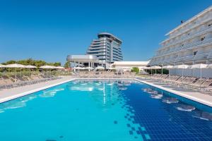 a swimming pool with chairs and a building at Hotel Olympia Sky in Vodice