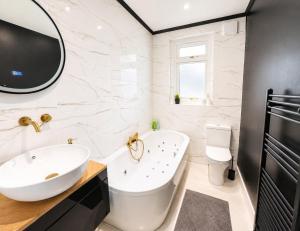 a bathroom with a white tub and a sink at Stylish 2BR House Parking & WiFi Sleeps 6 in Grangemouth +20 photos