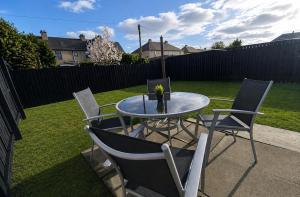 a table and chairs on a patio with a yard at Stylish 2BR House Parking & WiFi Sleeps 6 in Grangemouth
