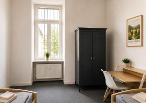 a bedroom with a black cabinet and a table and a window at Ermar Gästehaus in Baden-Baden