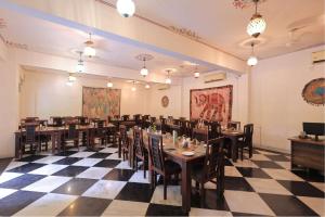 a restaurant with tables and chairs in a room with a checkered floor at Atulya Niwas in Udaipur