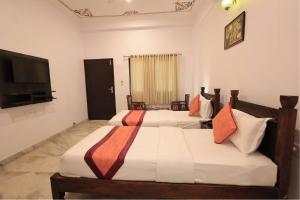 a bedroom with two beds and a flat screen tv at Atulya Niwas in Udaipur