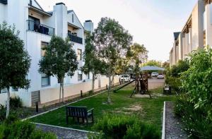 a park with a bench and a playground in front of a building at Ocean view in Johannesburg