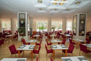 a restaurant with wooden tables and red chairs at LAICO Hammamet hotel in Hammamet