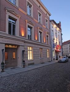 a building on a street with a car parked in front at Aparthotel Altes Schwedisches Konsulat in Stralsund